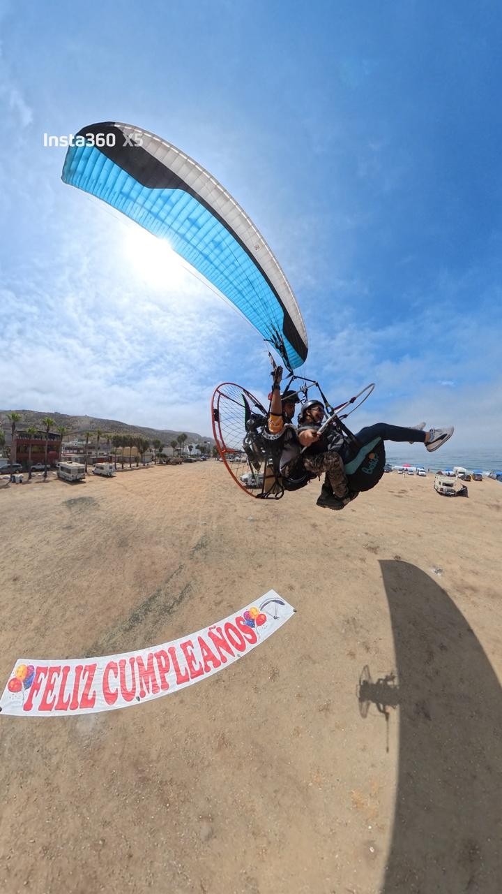 Vuelo en parapente con lona de feliz cumpleaños en la playa